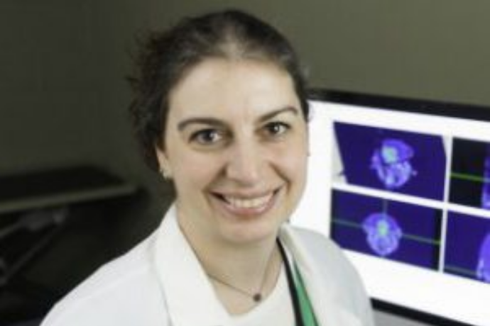 woman smiling with brain scans behind her on monitor
