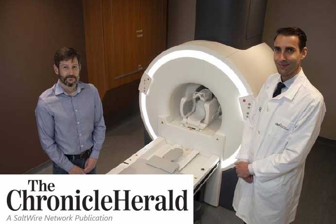 two men standing on either side of an MRI