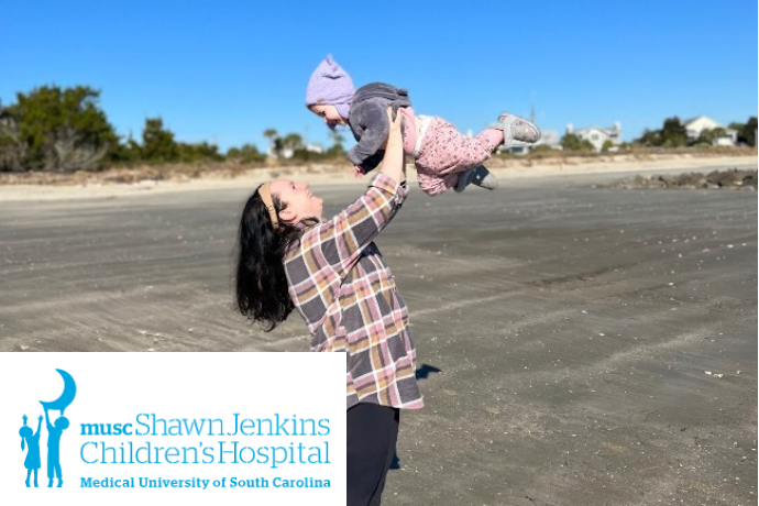 woman holding young child on beach